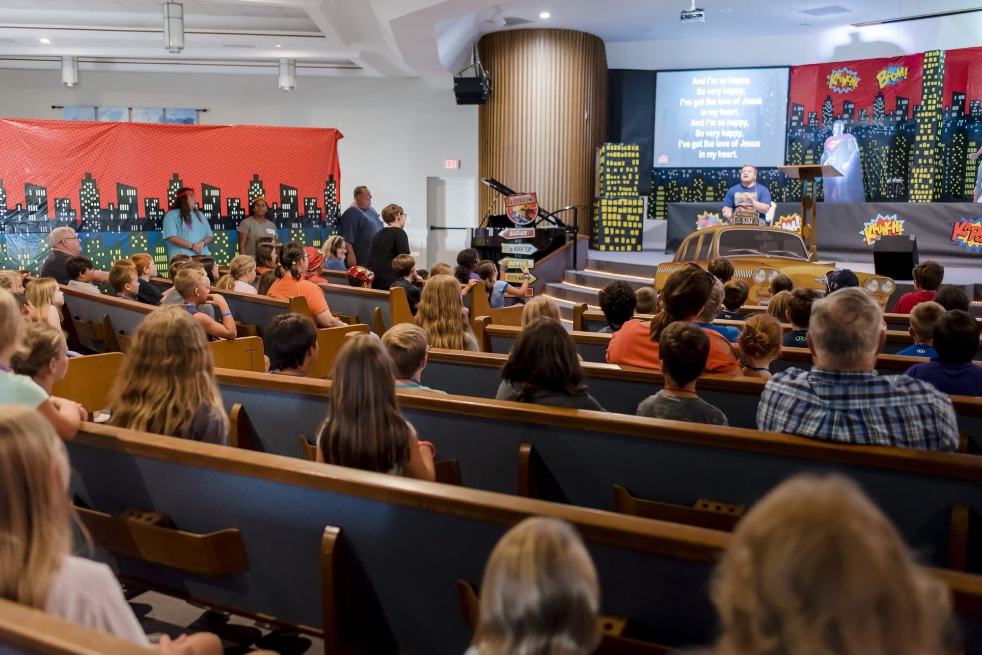 The Calvary Baptist auditorium filled with children and adults in the wooden pews during an evening service