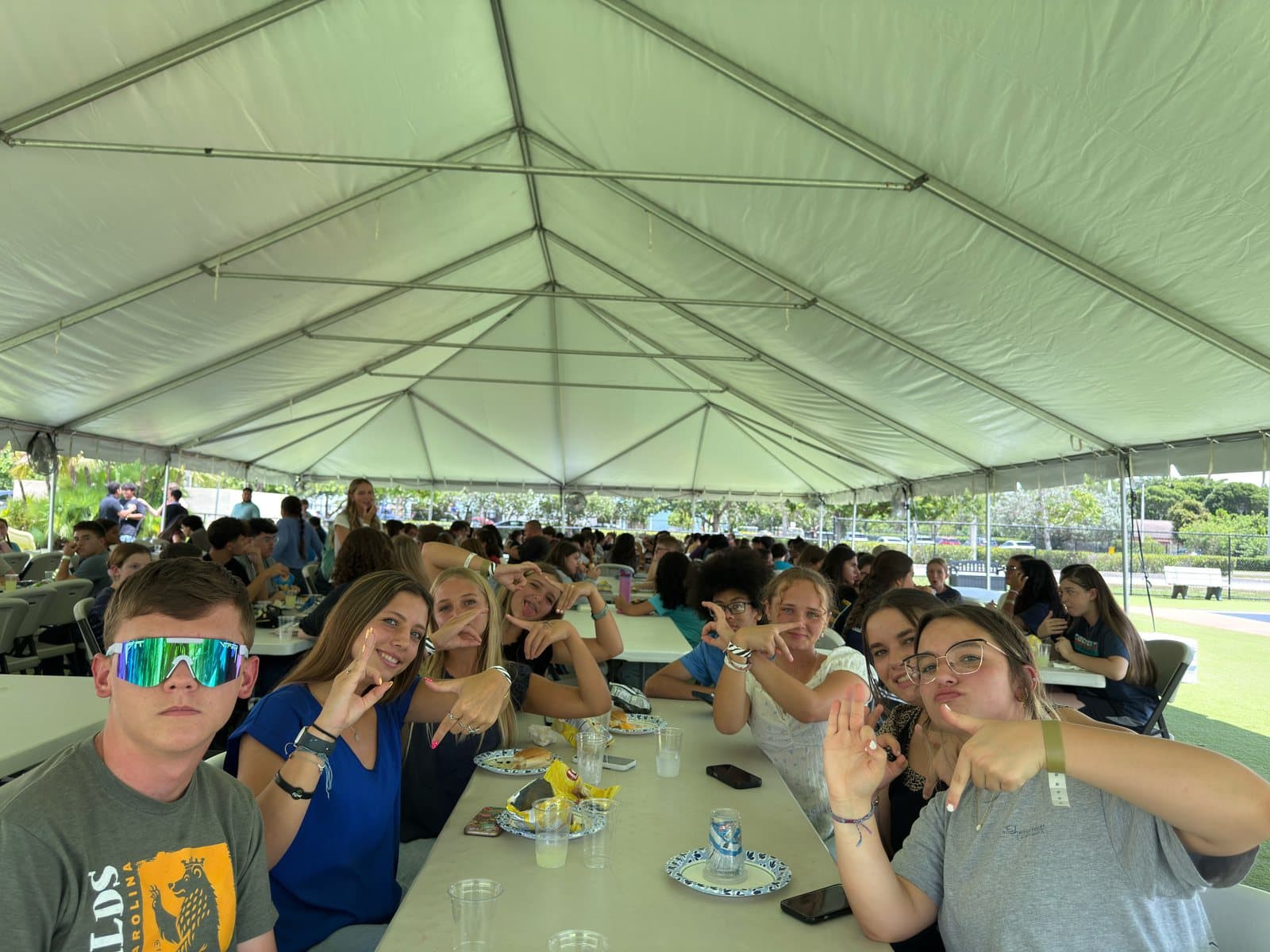 Students and leaders around long tables under a big white tent at camp