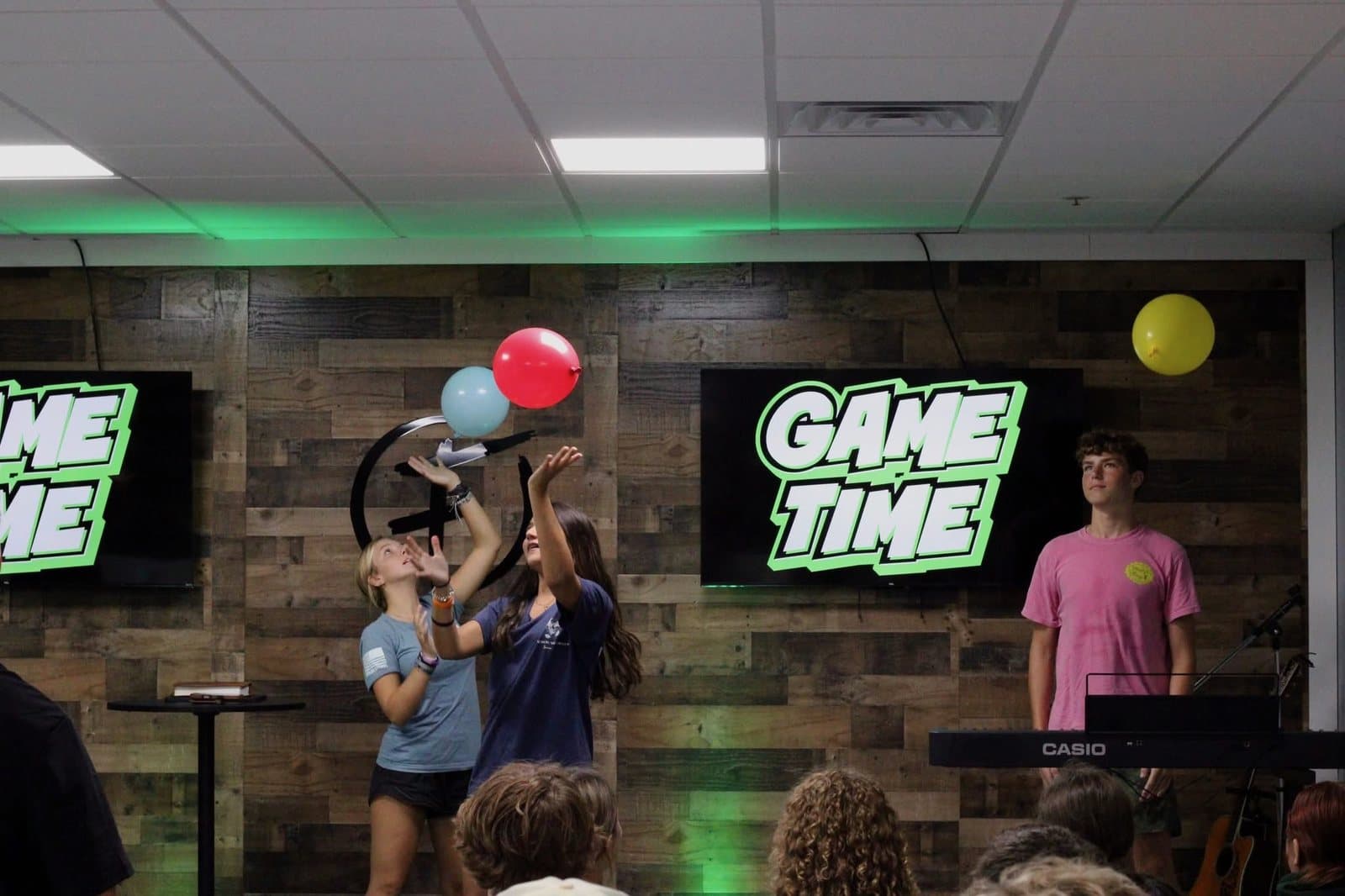 Students playing a balloon game on the FUSION stage under the words GAME TIME