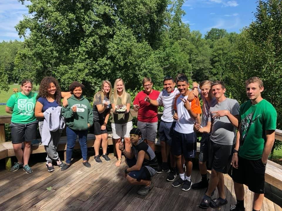 The teen group posing together on a wooden boardwalk under the trees during an outing