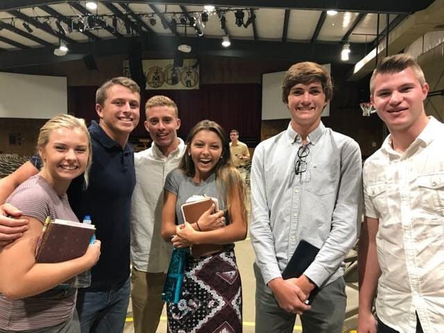 Five students standing together holding their Bibles after a service